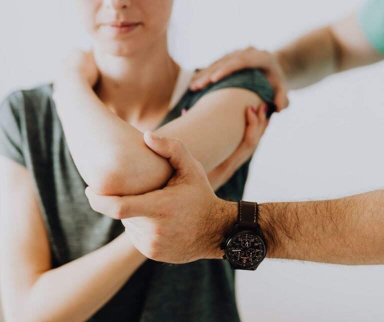 Chiropractor examining arm joint of female patient.